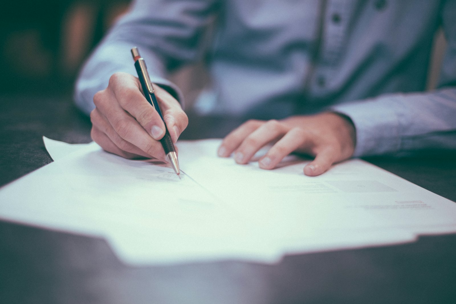 Signing notarized documents with a pen at a desk